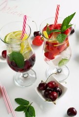 Detox water with strawberries, cherries, lemon and mint on white background