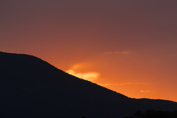 an orange sky behind a mountain 