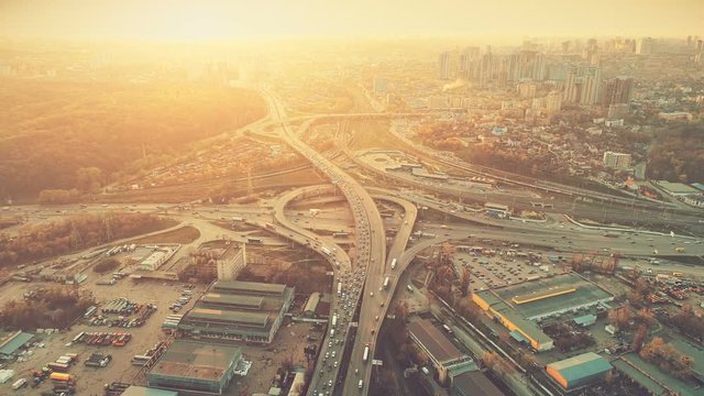 Aerial Drone Flight Footage of highway and overpass with cars and trucks. Camera Flies Over the Road Junction in the big city. Top view. Cityscape in sunset soft light. Instagram vintage filter toning