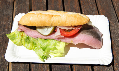 Matjesbrötchen mit Ziebeln, Tomate, Gurke und Salat auf Pappteller