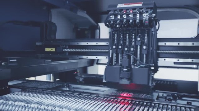 Automated Electronic circuit board production. Machine Produces Printed digital board, contract manufacturing. Manufacture of electronic chips. Robotic arm. Red light. High-tech. Full HD. Blue toning