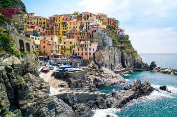 Fototapeta na wymiar The small fishermen village of Manarola, with its little fishing port and its colorful houses hanging to the cliff, is one of the five town of the Cinque Terre in Liguria.