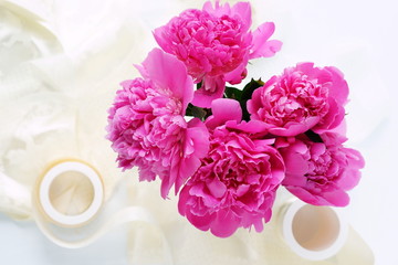 Beautiful bouquet of pink peonies in a vase and lace on a white background