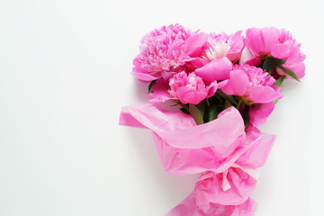 Beautiful bouquet of pink peonies in pink packing on a white background. top view. copy space