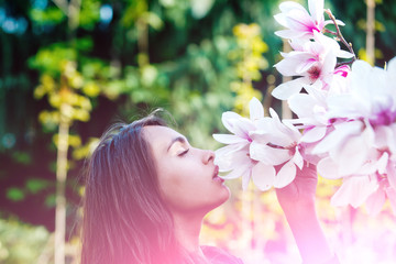 Fototapeta premium girl smelling pink, blossoming, magnolia flowers from tree