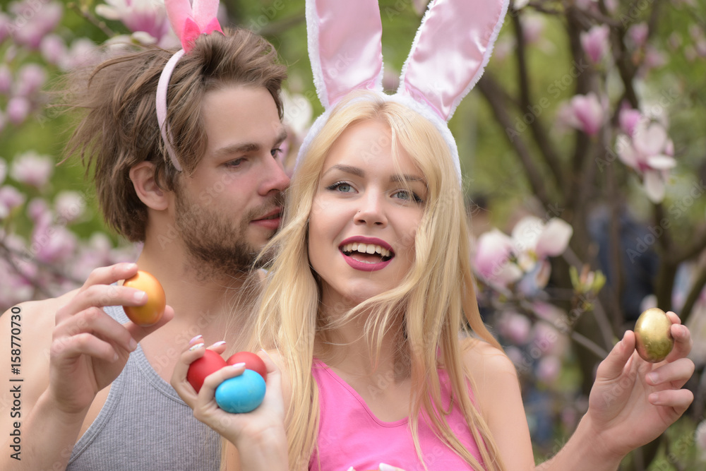 Wall mural couple in love with bunny ears holding colorful eggs