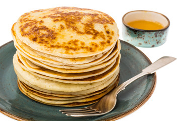Stack of fried vanilla pancakes on plate on white background