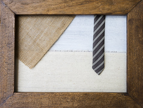 Hessian and canvas with black design necktie in old wooden picture frame, business and father's day concept