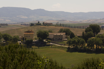 Hills surrounding Val D'orcia area in Tuscany region of Italy, with houses and cypress in the background