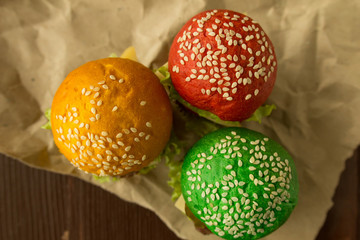 Multi colored burgers on cooking paper top view