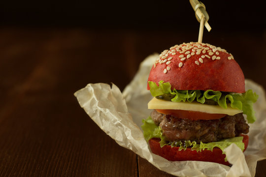 Burger in red bun on wooden table