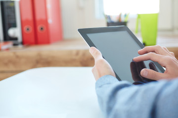 Men hand clicks a blank screen tablet computer closeup. Concept man working in the morning from home using tablet computer.
