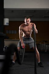 Fototapeta na wymiar Young Man Battling Ropes At Gym Workout Exercise