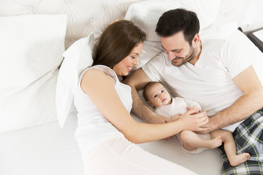 Happy family with newborn baby on the bed in room