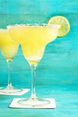 Lemon Margarita cocktails on vibrant turquoise with copyspace