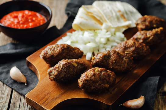 Minced meat sausage with onion, sour cream, pita and red bell pepper relish