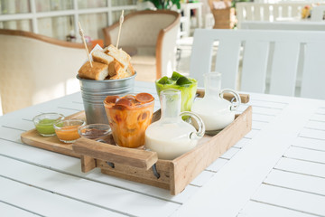 Coffee and green tea ice cubes with milk, Bread baked butter in bucket and dipping sauce, On the table.