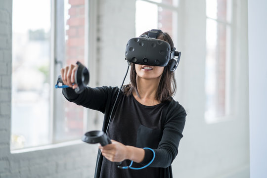 An asian woman wearing a virtual reality headset.