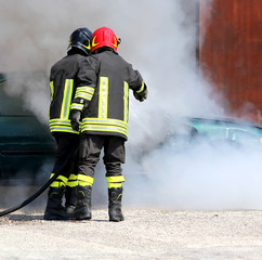 Obraz premium firefighters with uniform and protective helmet extinguish the f
