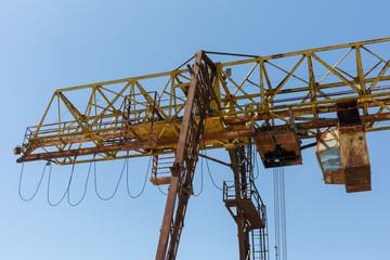 Rusty gantry crane on the background of blue sky.