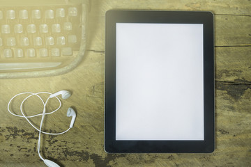 tablet with blank screen and a cup of coffee ear phone flower pot on the desk in coffee shop cafe,an office tablet with blank white screen ready for content text ,vintage tone,selective focus.