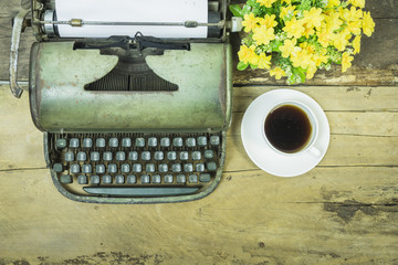  top view of Old typewriter with blank paper,retro typewriter on table ,Retro typewriter placed on wooden planks, typewriter and a blank sheet of paper and flower pot ,vintage tone,selective focus.