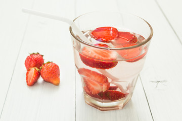 Fruit water in a glass on a white table. Organic strawberry.