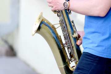 boy plays the saxophone in the street to passersby