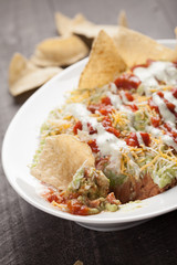  
Multi-Layer dip with guacamole, ranch, cheese, salsa, and refried beans with corn tortilla chips close up shot
