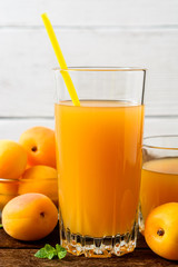 Fresh apricot juice and apricots on wooden table.