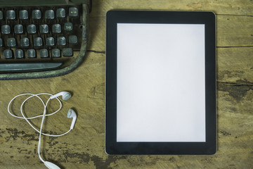 tablet with blank screen and a cup of coffee ear phone flower pot on the desk in coffee shop cafe,an office tablet with blank white screen ready for content text ,vintage tone,selective focus.