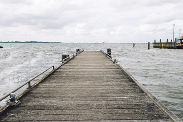 Empty wooden pier with dark stormy clouds over Northern  Sea in The Netherlands