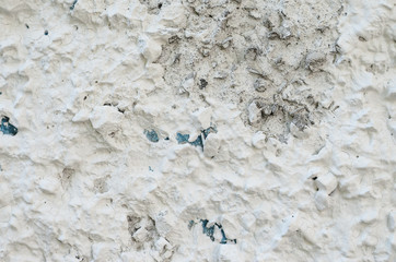 Old white concrete wall with many protruding stones