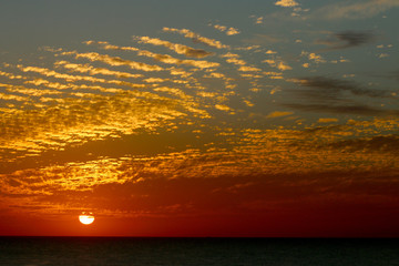 Obraz premium sunset in winter, cloudy sky, sun ray in the sea of clouds