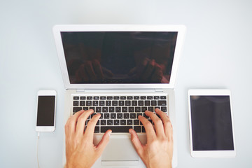 High angle view of unrecognizable manager using laptop for business, other devices near computer