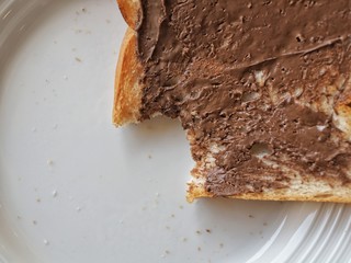 Fototapeta premium Sliced bread and chocolate spread with a bite taken.