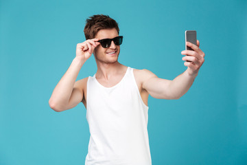 Happy man in sunglasses make selfie by phone