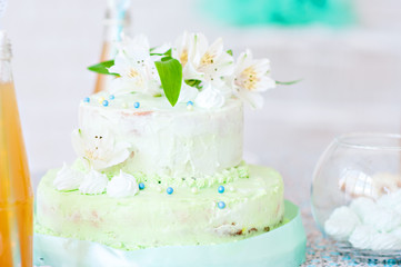 Mint-colored cake with handmade cookies and bottled juice