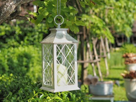 White Iron lantern hanging on tree in the garden. Concept of exterior decoration.