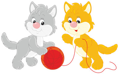 Little kittens playing with a red clew of yarn