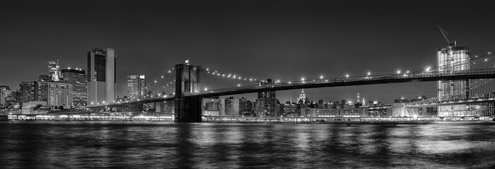 Black and white panoramic photo of Brooklyn Bridge at Night, NYC.