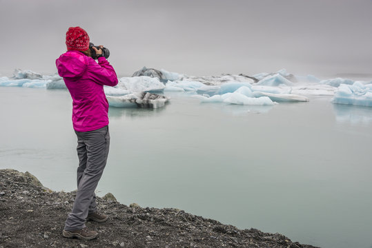 Girl photographer at Jokulsarlon glacier lake lagoon. Vatnajokull National Park. Iceland.