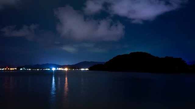 Timelapse showing moving clouds, lightning and city lights at night. The bay with the sea, islands and a distant city are clearly visible. Beautiful landscape from Langkawi Malaysia