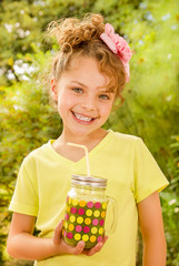 Beautiful young girl wearing a yellow t-shirt, holding a healthy smoothie drink made of super foods, fruits, nuts, berries