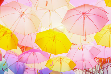 Hanging colorful umbrellas  backgroundon the street and blue sky.Colourful umbrellas urban street decoration. Hanging Multicoloured umbrellas. vintage color in Holiday tone,selective focus