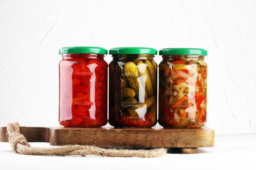 Jar with variety of pickled vegetables. Carrots, field garlic, cucumber in glas. Preserved food