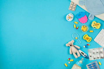 Assorted pills and bear toy with electronic thermometer on blue backround