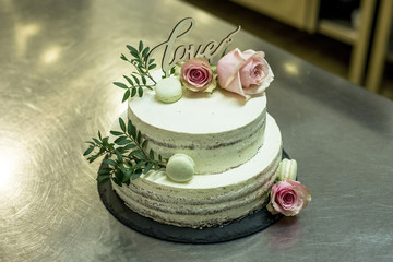 Beautiful wedding cake with cream With text Love on top pink flowers roses