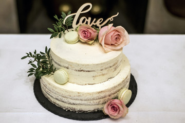 Obraz na płótnie Canvas Beautiful wedding cake with cream With text Love on top pink flowers roses