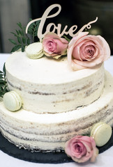 Beautiful wedding cake with cream With text Love on top pink flowers roses